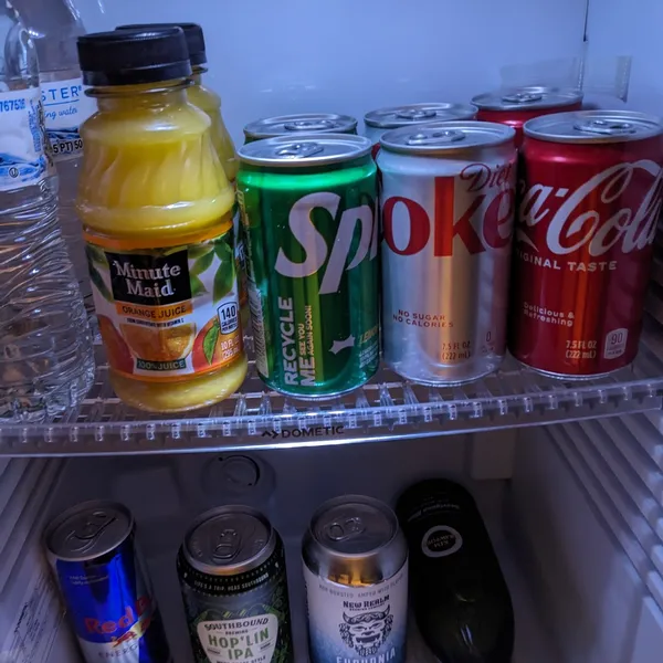 Open minifridge with water, OJ, coke, diet coke, and sprite