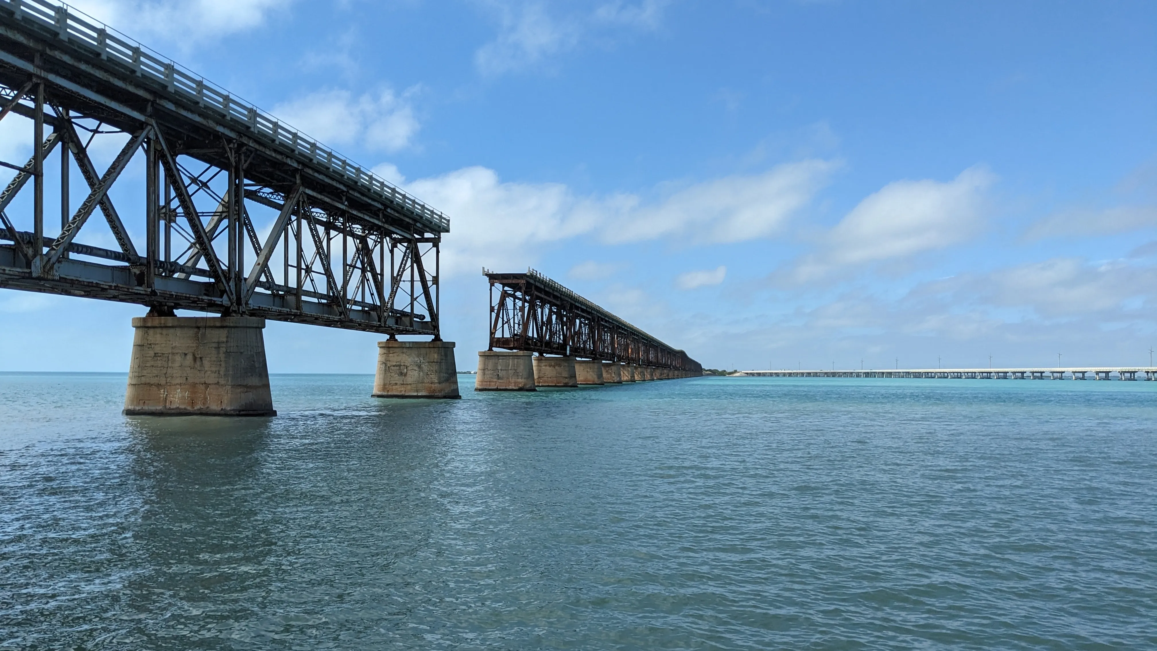 A long bridge disappearing to the horizon with a missing span